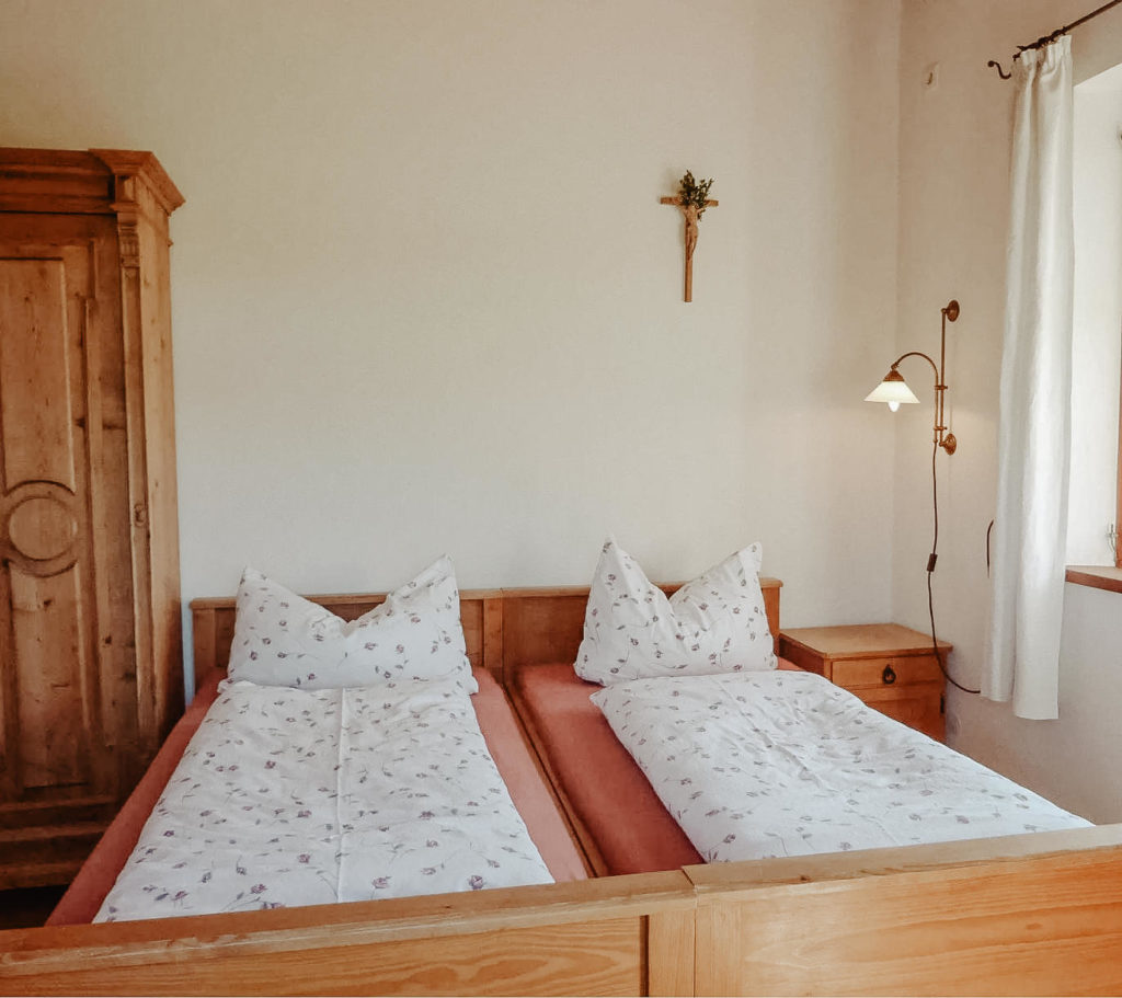 Ein helles Schlafzimmer aus Vollholzmöblen mit einem Doppelbett, einem Schrank und einem Nachtkästchen