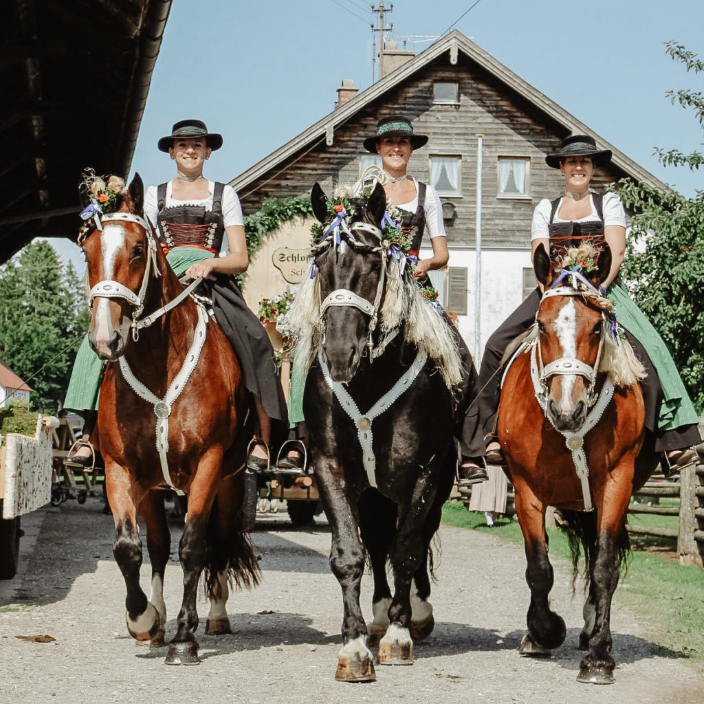 Drei Frauen in Tracht auf traditionell geschmückten Pferden für den Leonhardi Ritt