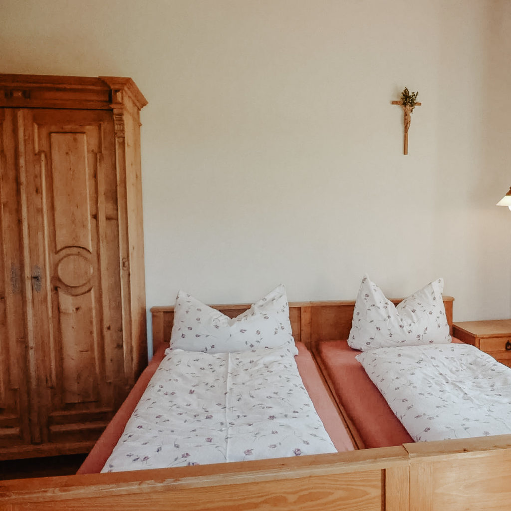 Ein helles Schlafzimmer aus Vollholzmöblen mit einem Doppelbett, einem Schrank und einem Nachtkästchen
